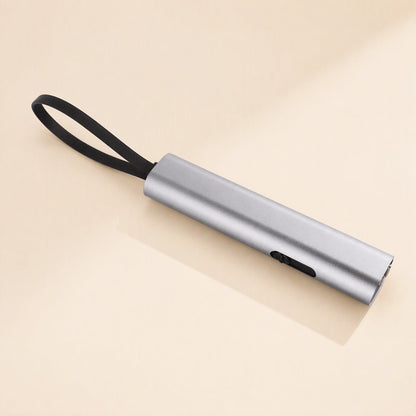 Quickcord – Silver cylindrical cable case with a black strap loop and a side slider, lying on a cream surface