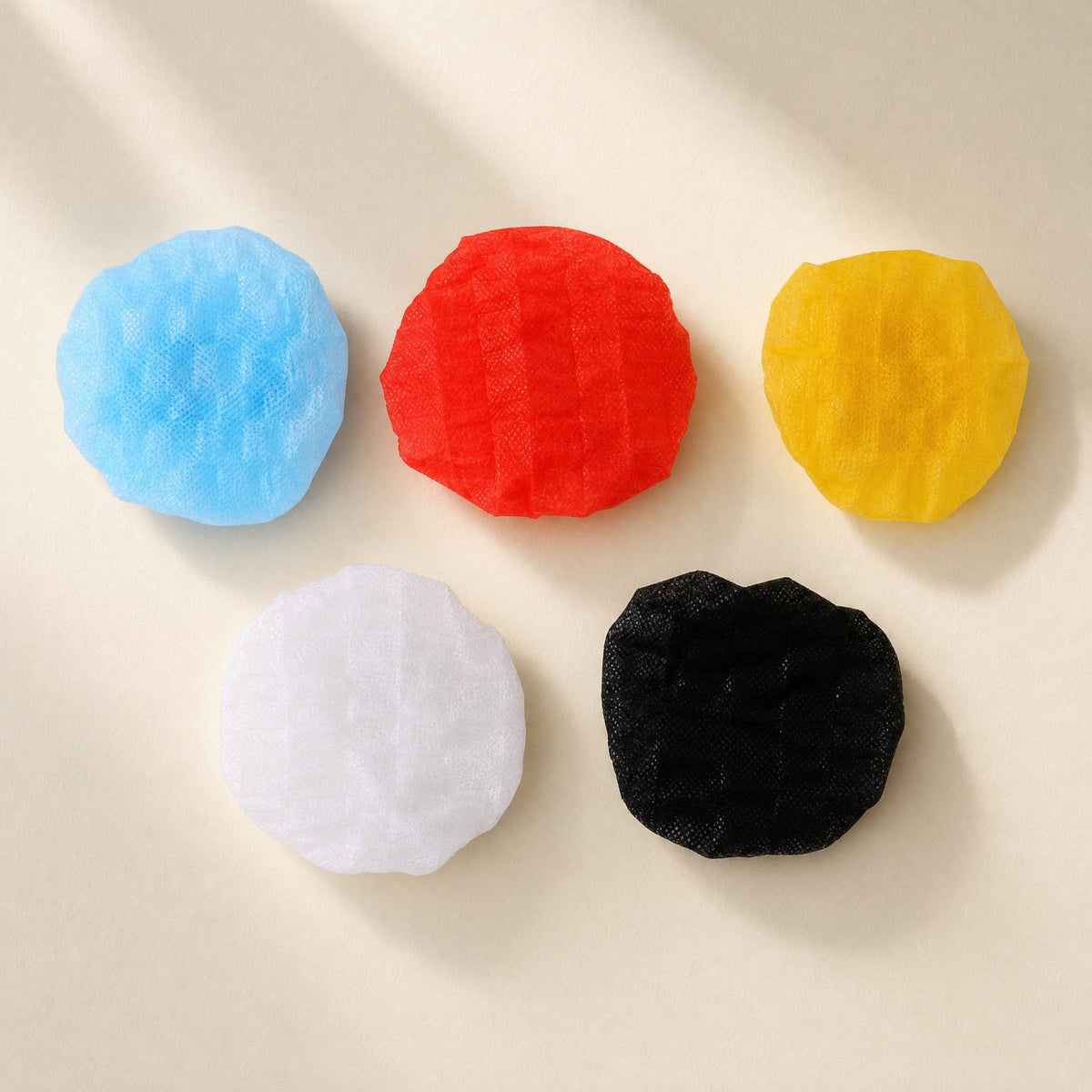 Freshveil – Five covers in blue, red, yellow, white and black laid flat in a row on a cream surface