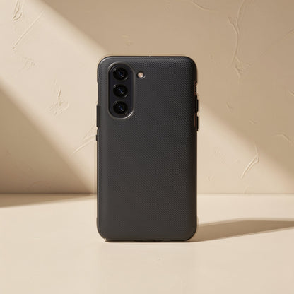 Flipgrain – Black textured case back with triple camera cutout, shown on a cream surface in angled sunlight
