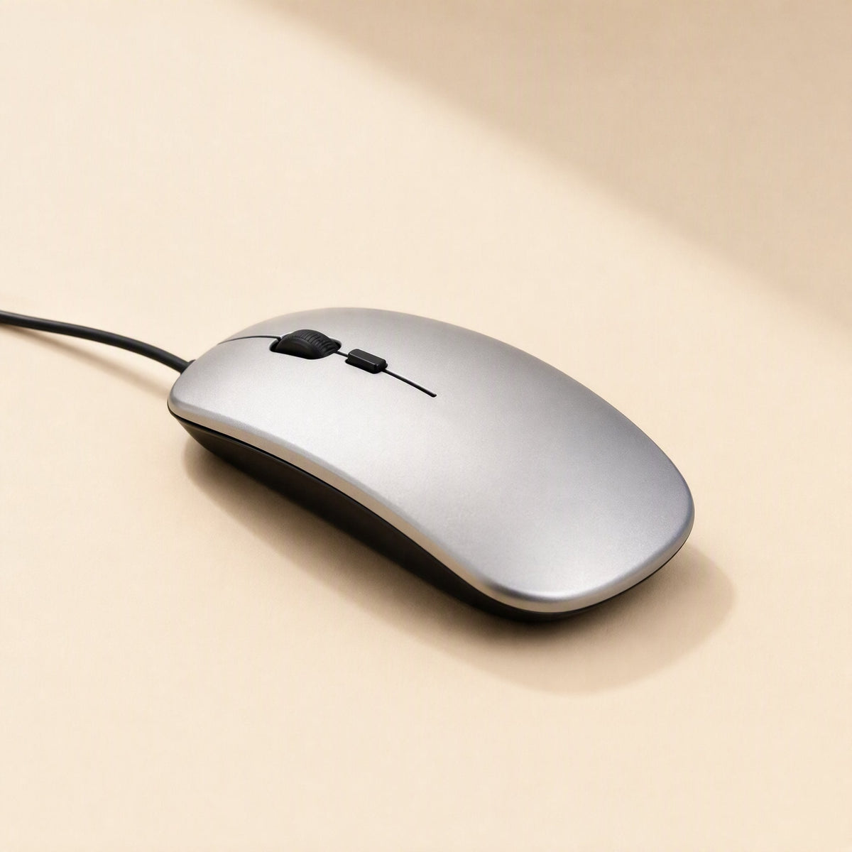 Clickfour USB Wired Mouse in silver with black trim and cable trailing left, on a cream surface