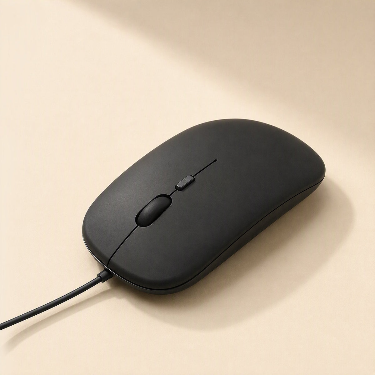 Clickfour – Slim black mouse angled from the side with the cable exiting at the bottom left on a beige background