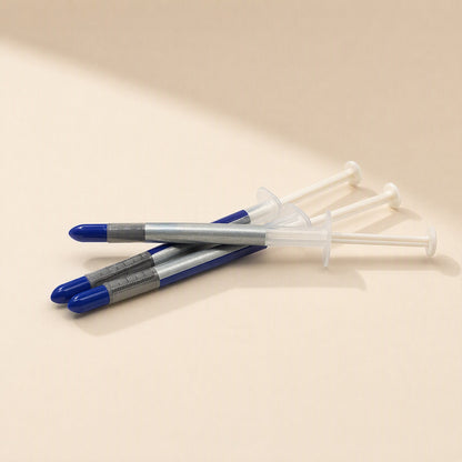 Thermspread – Three thermal paste syringes stacked in a loose pile, blue caps and gray measurement markings facing left