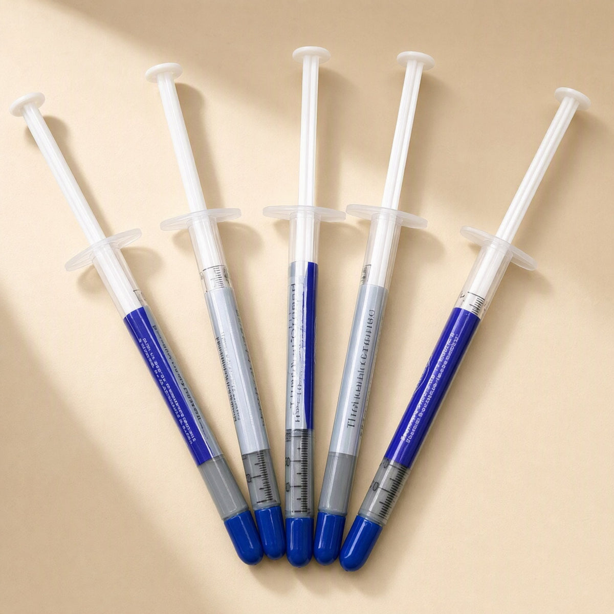 Thermspread – Five thermal paste syringes fanned out in a row, showing printed labels and graduated markings
