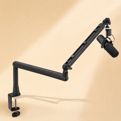 Swingreach microphone cantilever bracket clamped to a desk, holding a studio mic over a beige backdrop