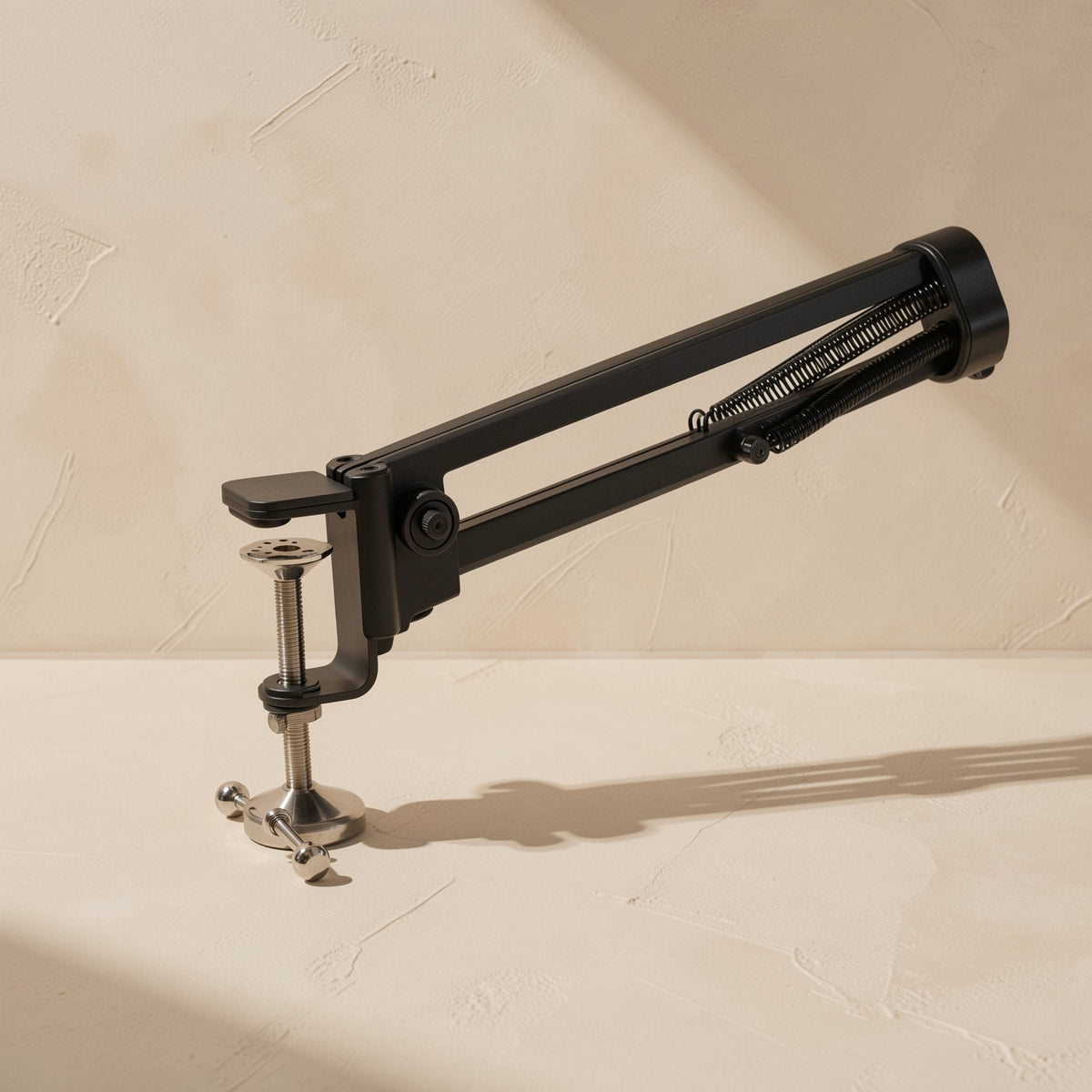 Clipgrip – Black desk clamp with silver screw and spring-loaded arm base, seen from a low angle on a pale surface