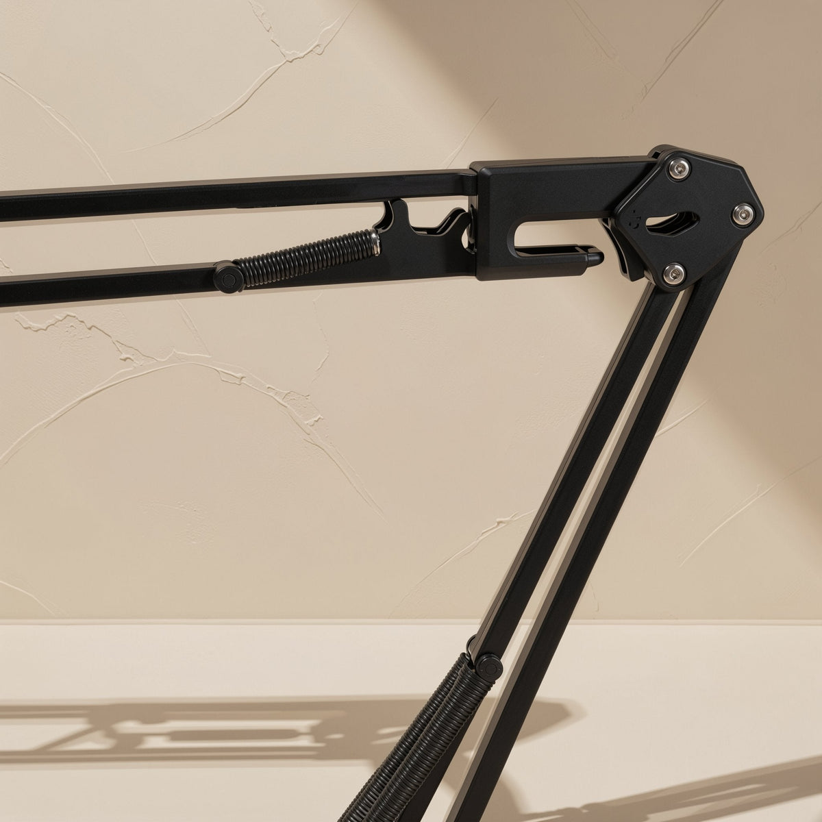 Clipgrip – Close-up of the arm's pivot joint, with bolts and a coiled spring on black metal tubing
