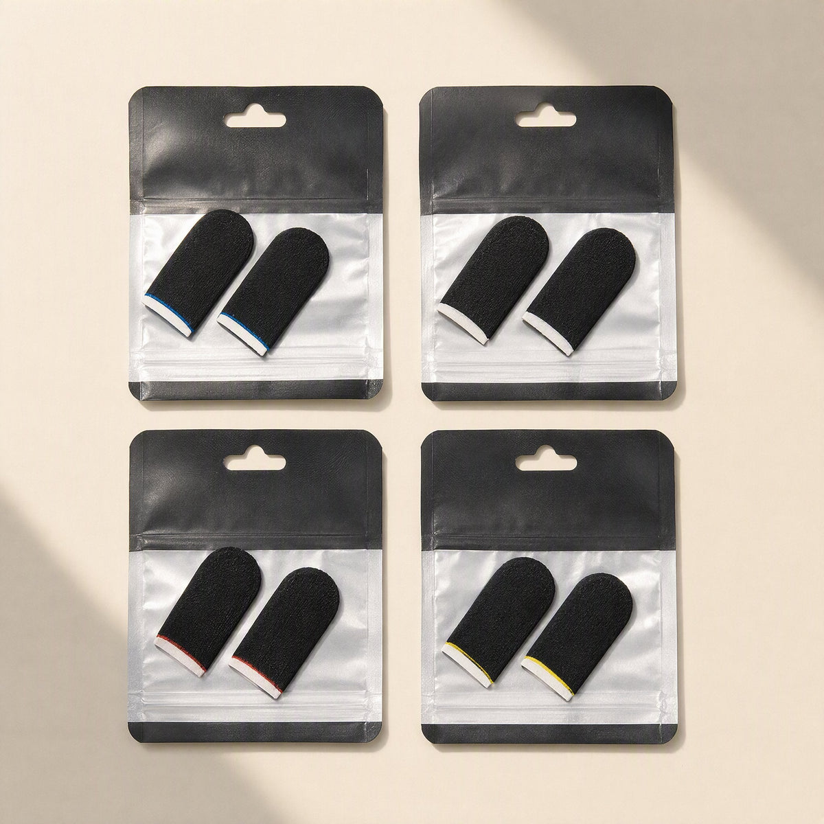 Gamegrip – Four packs of black finger sleeves with blue, white, red and yellow trim in clear zip bags on beige