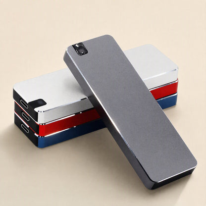 Solidvault Portable SSD in gray metal laid across a stack of silver, red and blue drives on beige