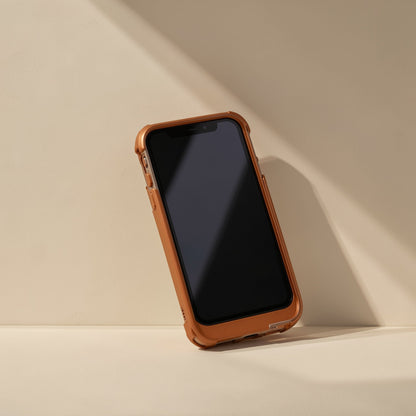 Linkweave – Orange protective phone case on a smartphone leaning against a beige wall in soft shadow