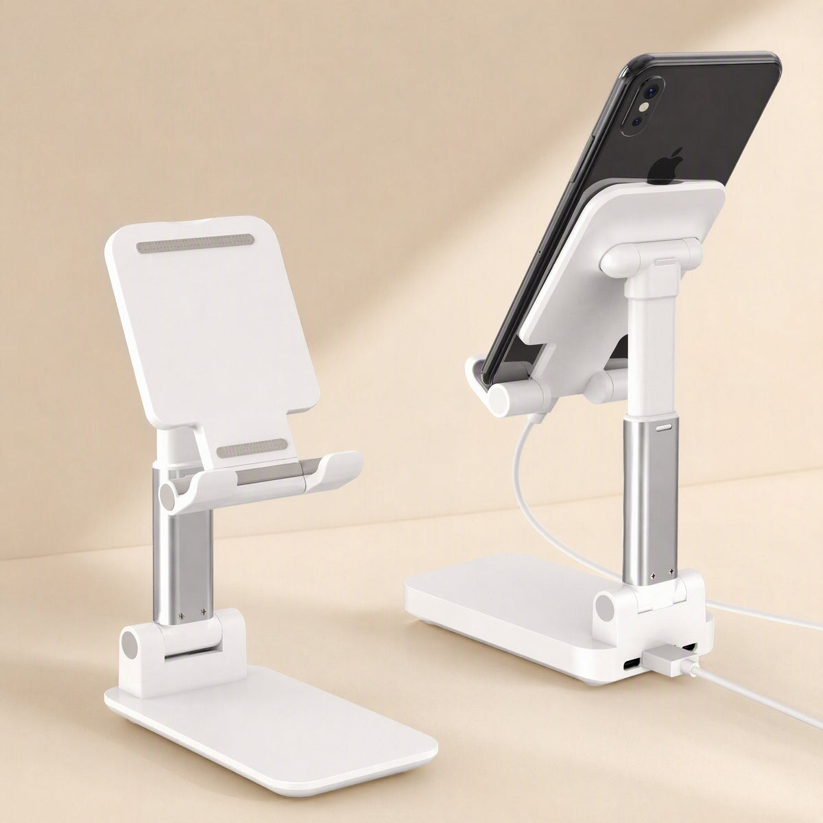 Fliprest – White holder with silver stem, one holding a phone with a charging cable plugged into the base