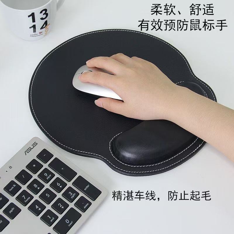 Wristhide – Black round mouse pad with white stitching and wrist cushion, hand resting on a silver mouse beside a keyboard