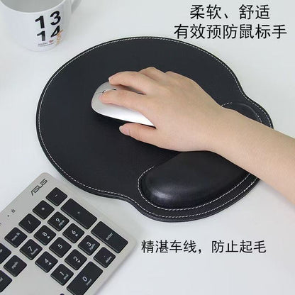 Wristhide – Black round mouse pad with white stitching and wrist cushion, hand resting on a silver mouse beside a keyboard