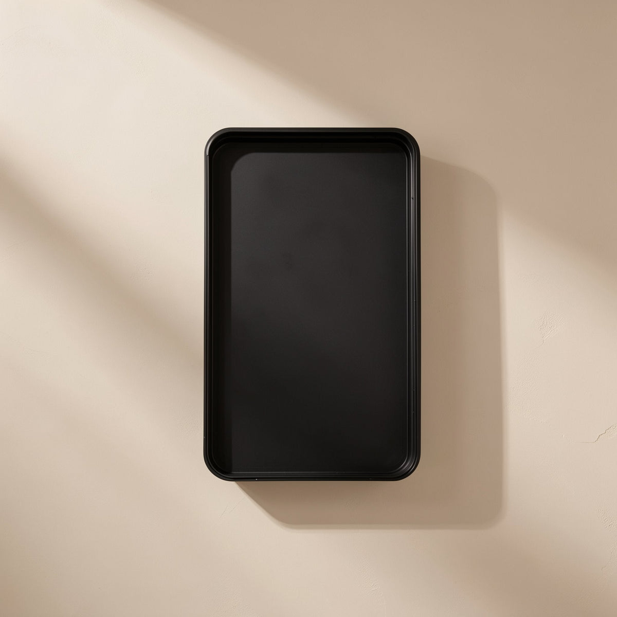 Empty black rectangular case seen from above against a beige wall with soft shadow, Bitbundle 115-in-1 set