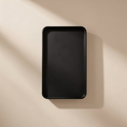 Empty black rectangular case seen from above against a beige wall with soft shadow, Bitbundle 115-in-1 set