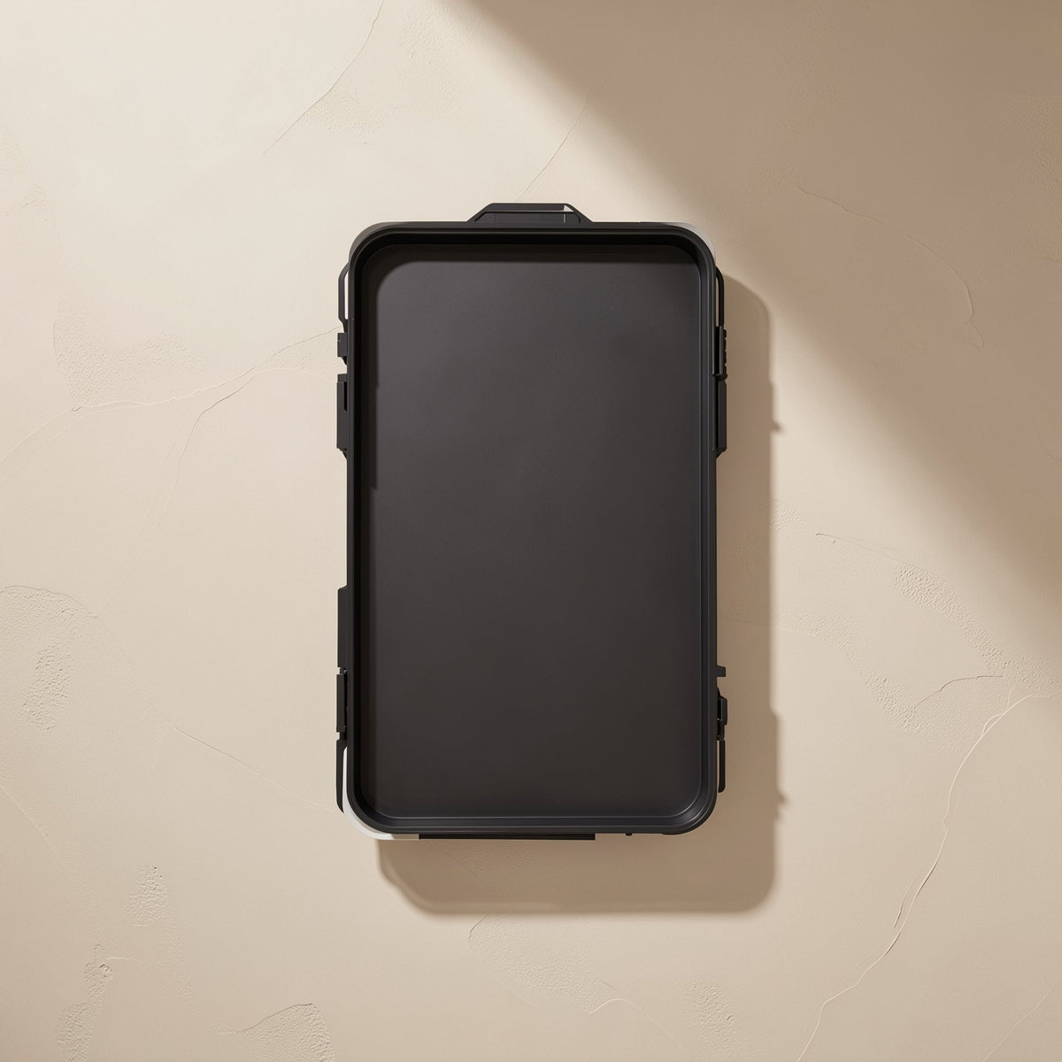 Bitbundle – Back of the black screwdriver set case with latches and a hanging tab on a cream textured wall