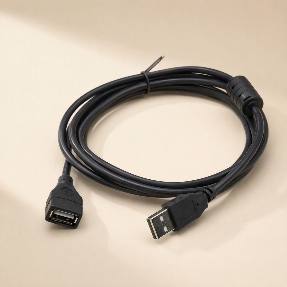 Copperreach – Coiled black USB extension cable with ferrite bead, male plug in front and female port at left