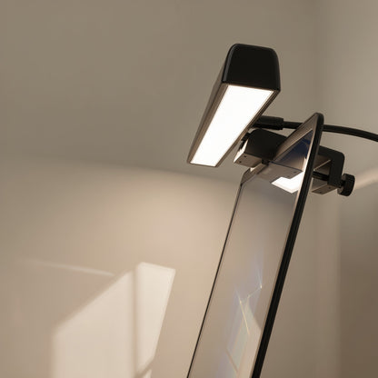 Taplume – Close-up of a black screen lamp with glowing light panel clipped to a monitor edge with a thumbscrew