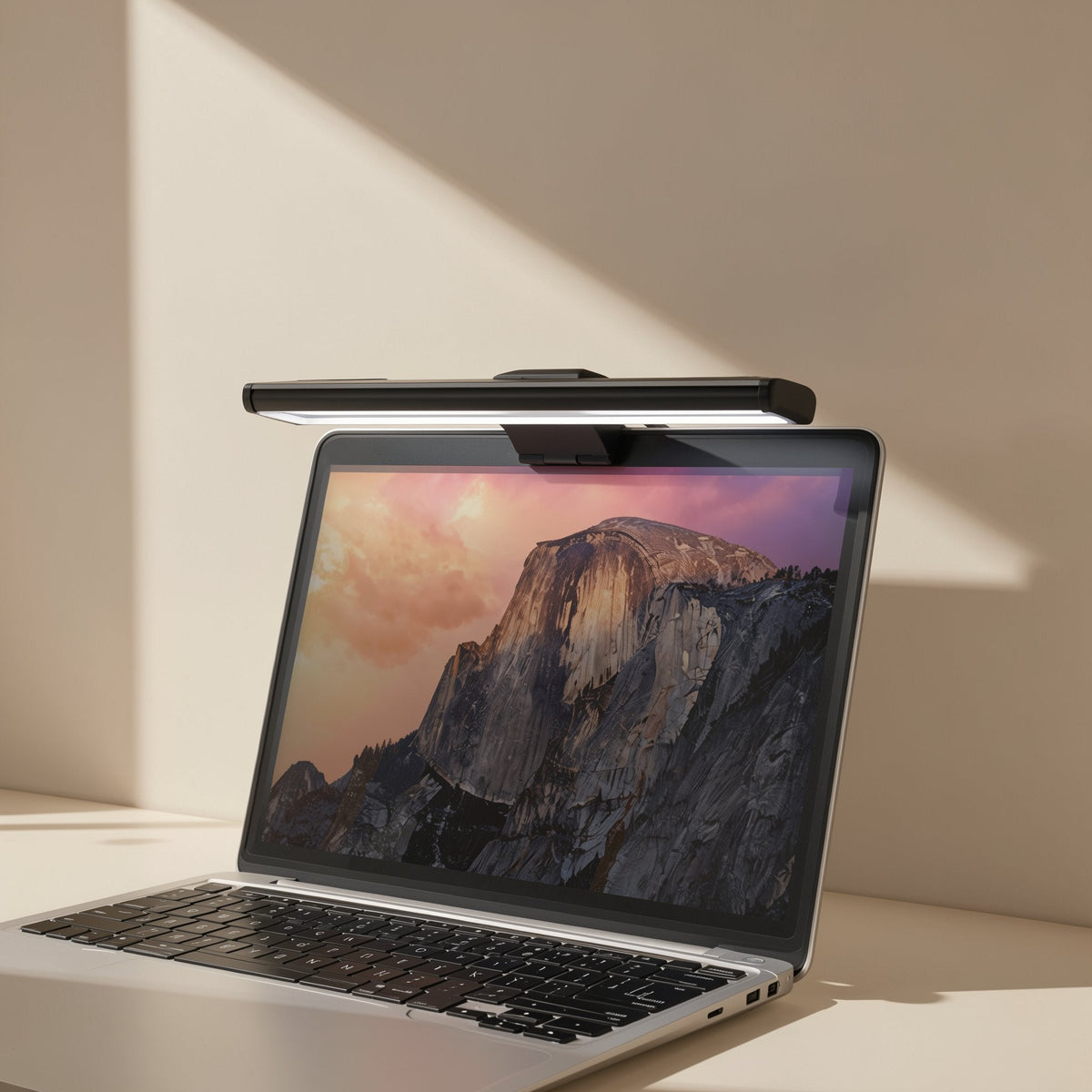 Taplume – Slim black screen lamp resting on top of an open laptop showing a mountain landscape
