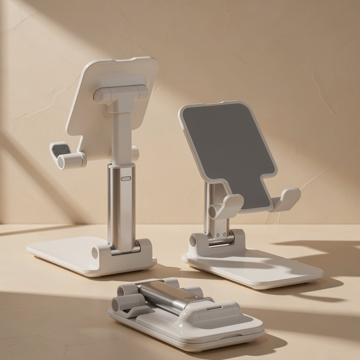 Foldstand folding phone stand in white and silver, shown extended upright and folded flat on a beige surface