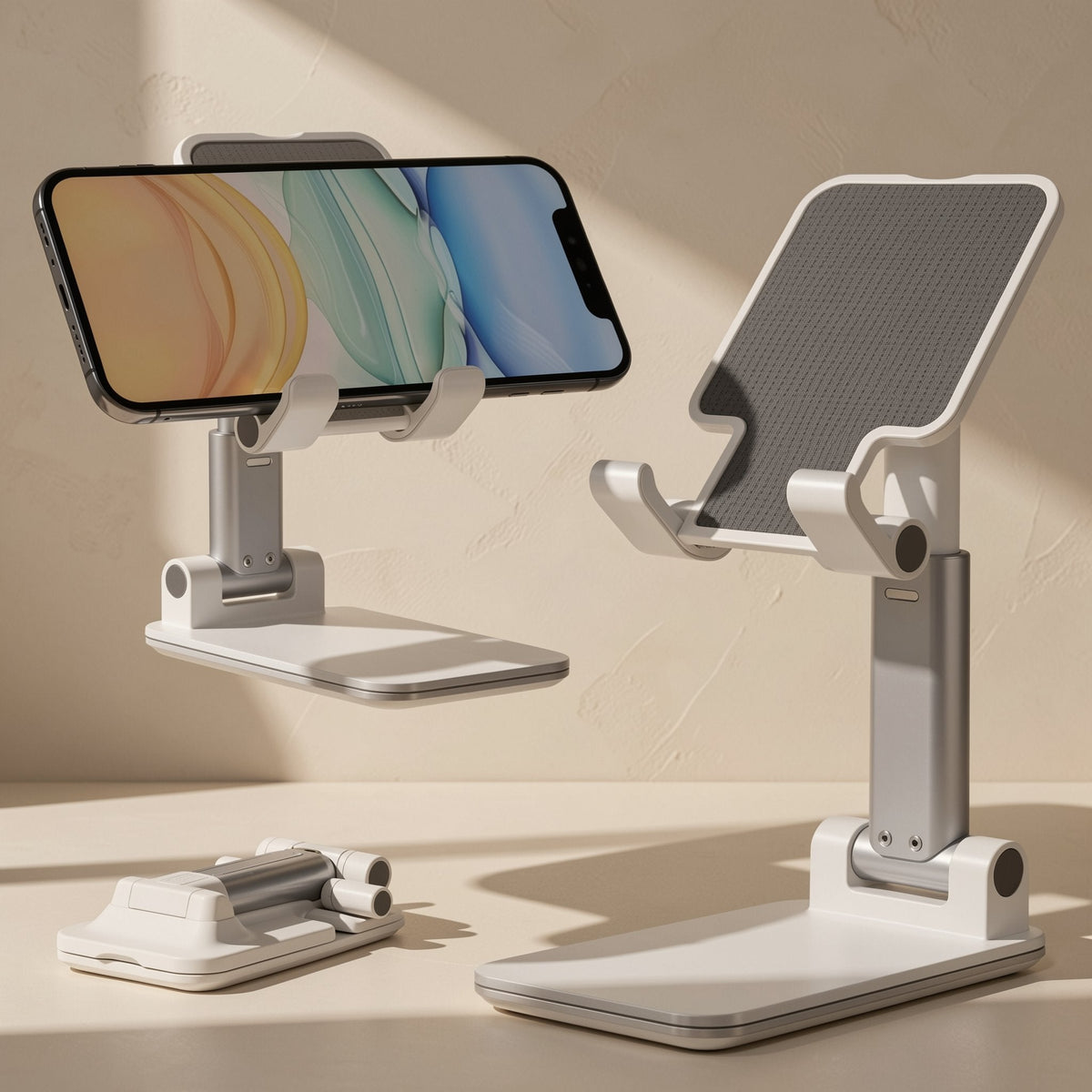 Foldstand – White folding stand holding a phone in landscape beside an extended stand and a folded one, silver arm visible