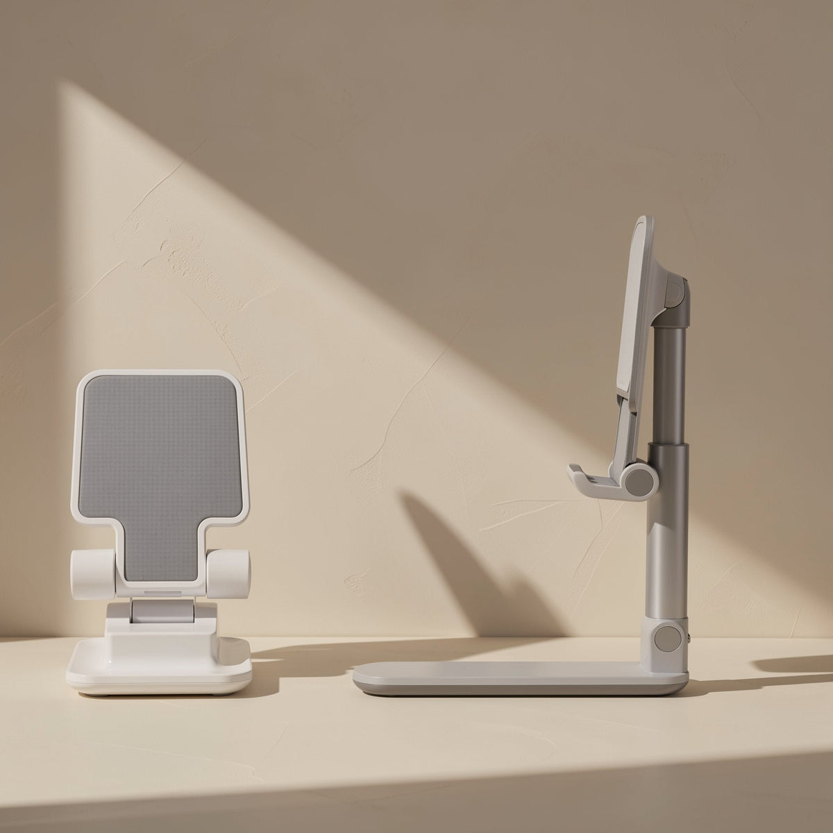 Foldstand – Front and side views of white stands with silver adjustable arm and grey grip pad against a beige wall