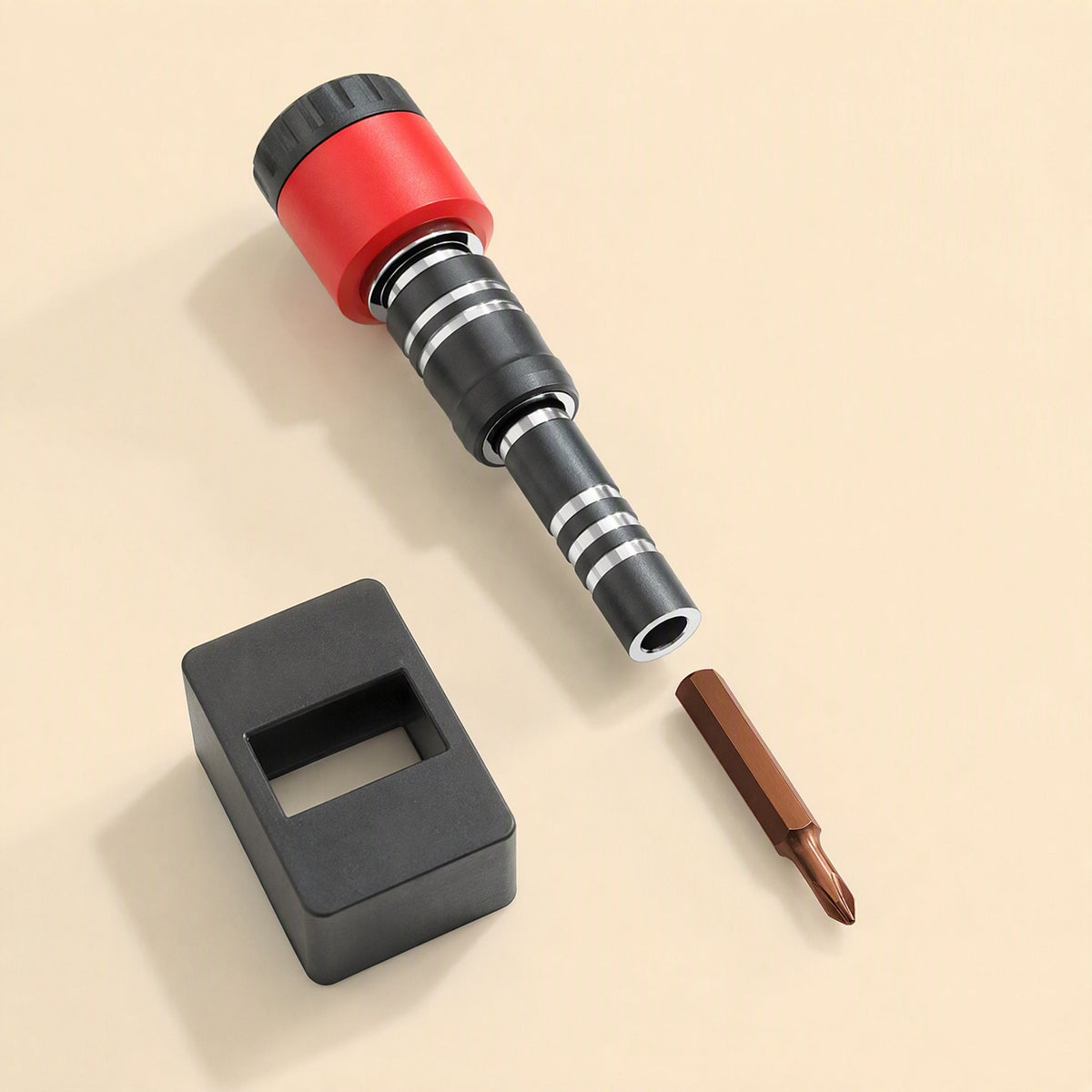 Magnetwist – Red and black screwdriver handle with a copper Phillips bit beside a black magnetizer block on beige