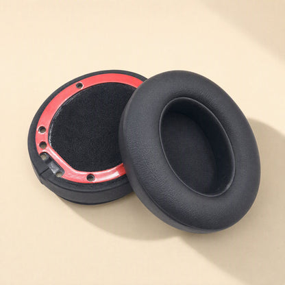 Leatherhug – Black headphone ear cushion beside an upturned one showing its red mounting ring and black fabric lining