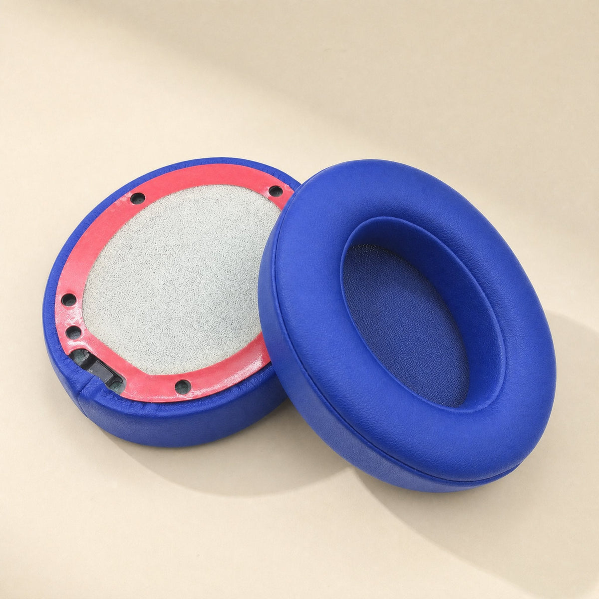 Leatherhug – Bright blue ear cushion standing beside an upturned one with a red-pink mounting ring and gray lining