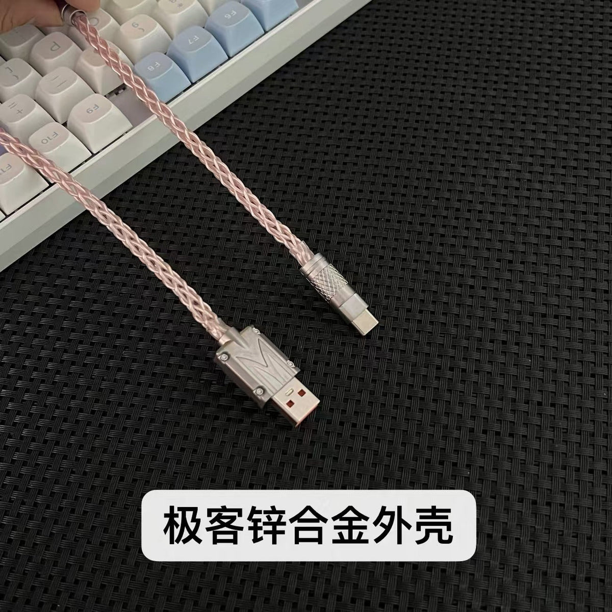 Braidlink – Pink braided cable with metal USB-A and USB-C connectors held above a white and blue keyboard