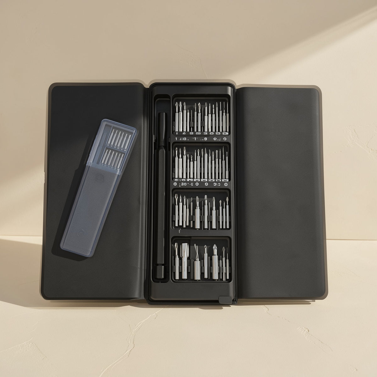 Phonebit – Open black case with a clear bit holder beside the driver handle and four rows of bits on a cream background