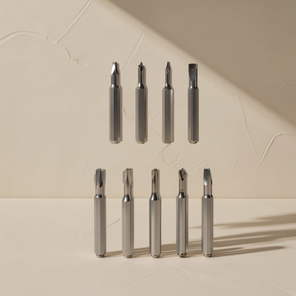Phonebit – Nine metal screwdriver bits in two rows with Phillips, flat and star tips on a cream surface
