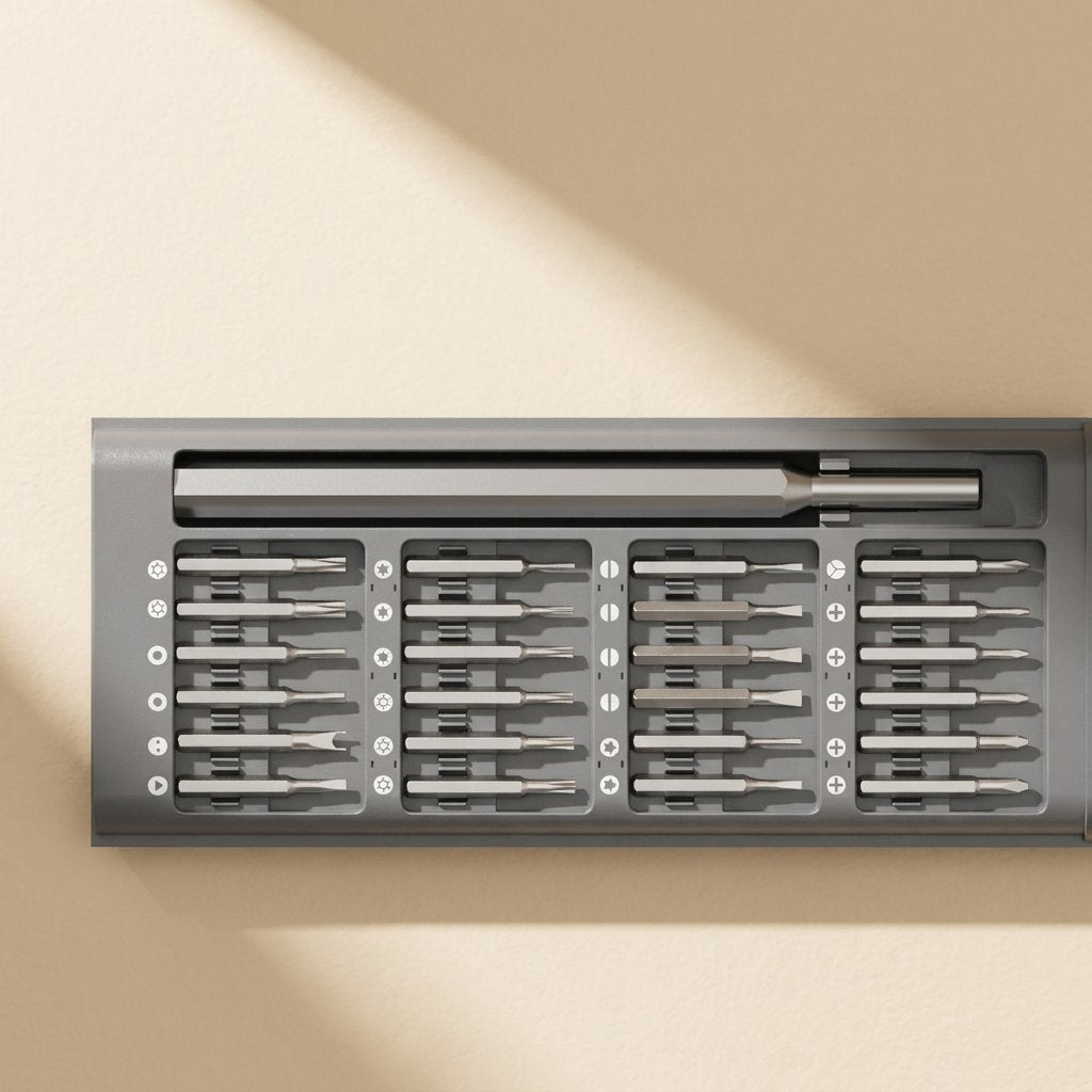 Phonebit – Top view of 24 bits in four rows, each with a marked slot, beside the long metal handle in a grey tray