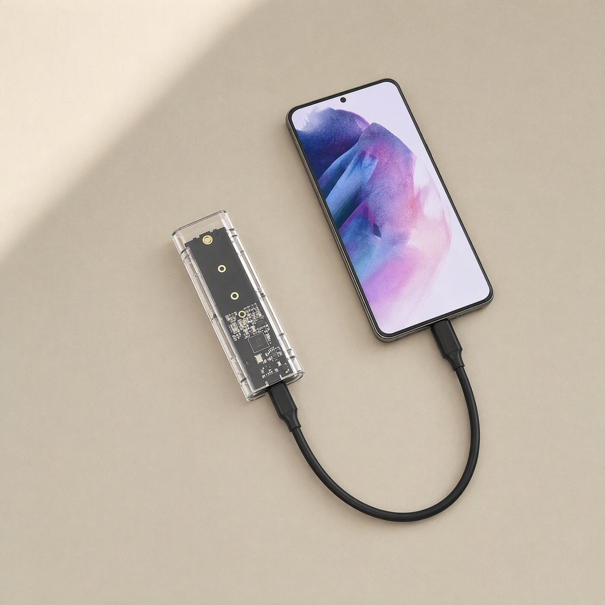 Driveclear – Clear enclosure connected by a short USB-C cable to a smartphone with a purple-blue screen