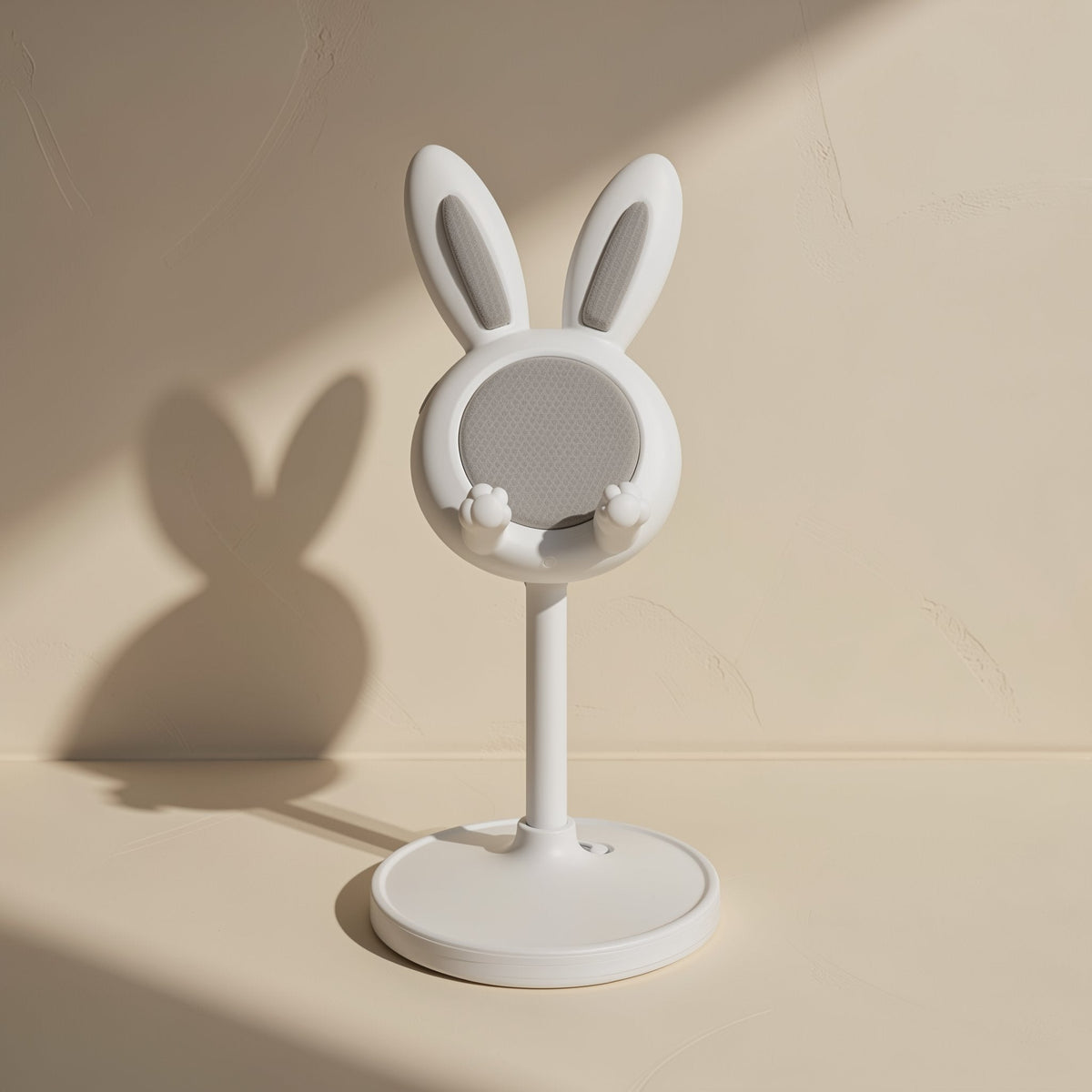 Bunnyrest – White bunny phone stand with grey grip pad and paw clips, casting a rabbit-shaped shadow on a beige wall