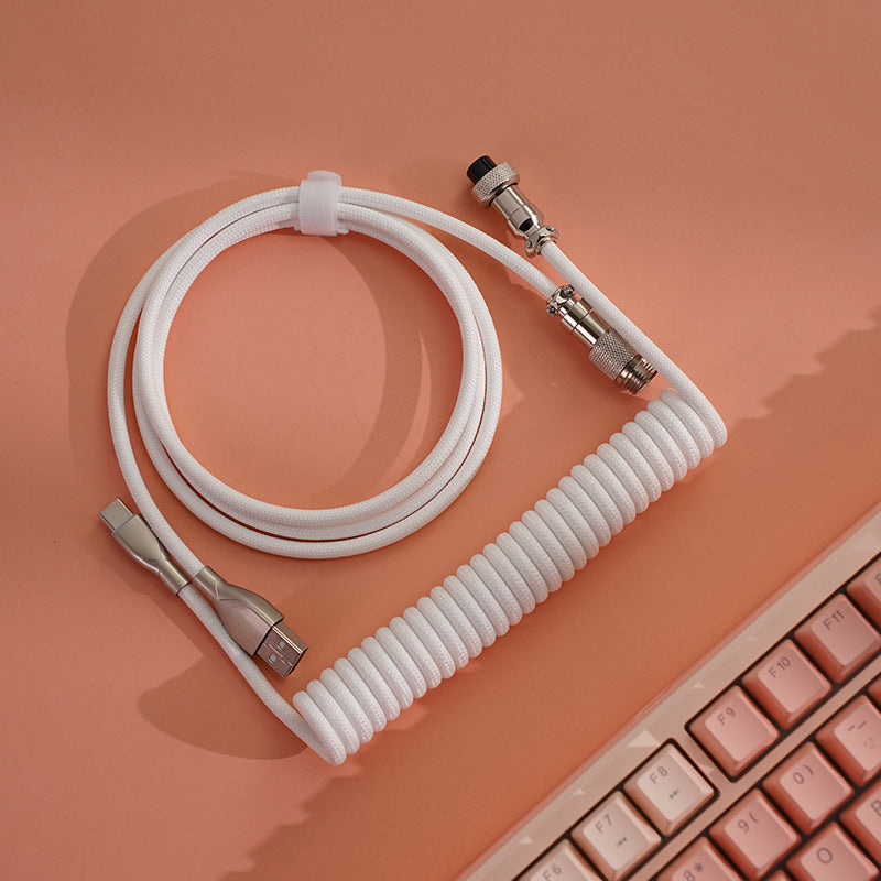 Springloop Magnetic Coiled Type-C Keyboard Cable in white, coiled on a peach surface beside a pink keyboard