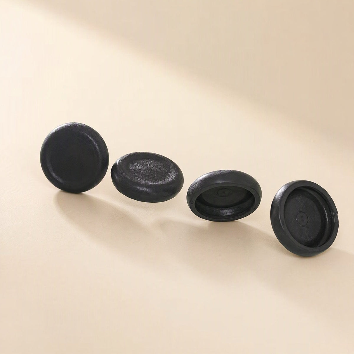 Thumbtread – Four black round caps arranged in a row, shown from different angles including the underside