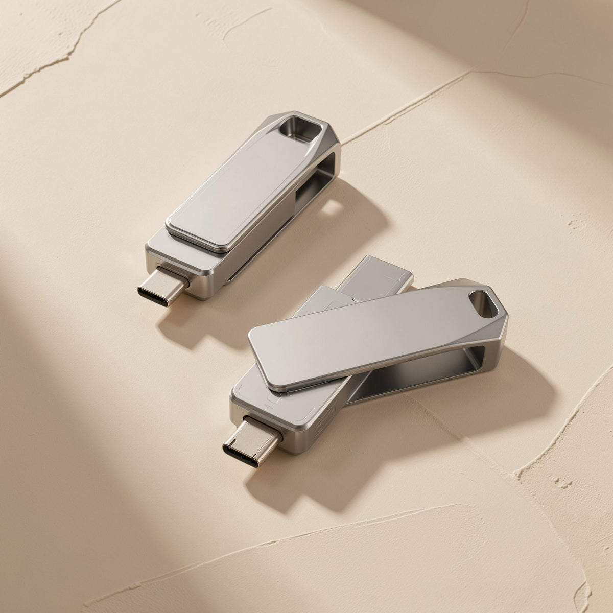 Typeflash – Two silver metal flash drives angled together, each showing a USB-C connector, on a textured beige surface