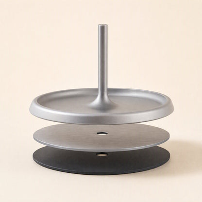 Hookrest – Stand base disassembled into layers: silver tray with post, brushed metal disc and black disc, with a center hole