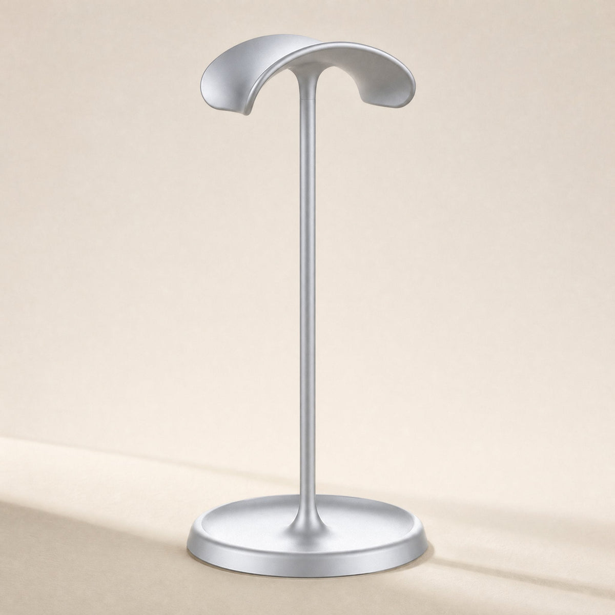 Hookrest – Front view of a single silver stand with a curved headband rest and a round dish base on a cream background