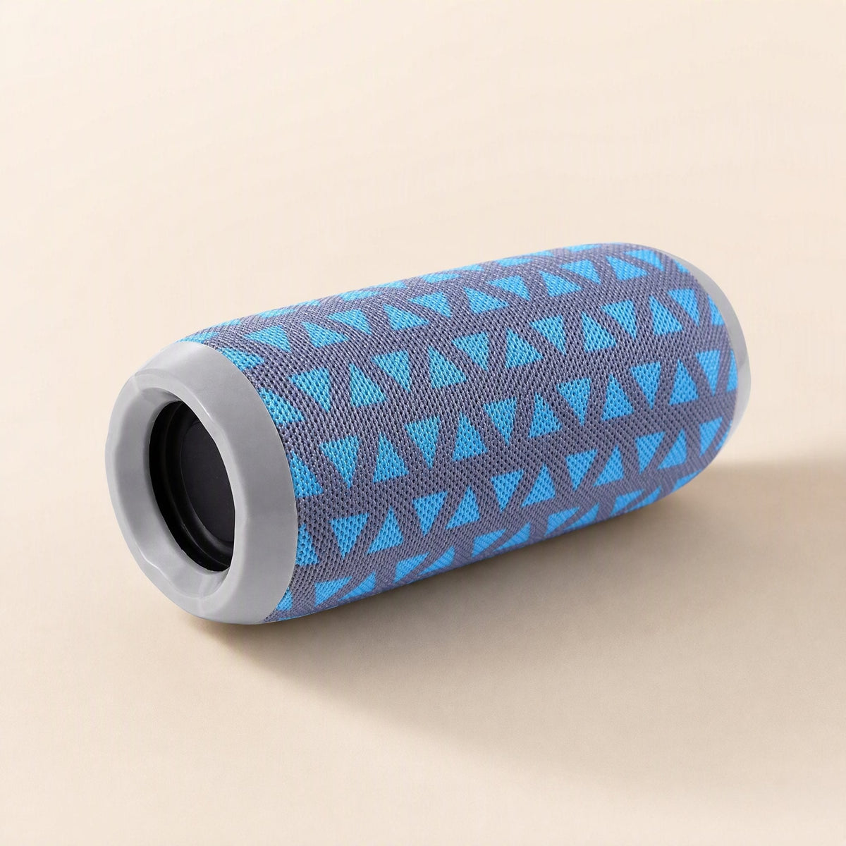 Pocketbeat – Blue and grey triangle-patterned speaker lying on its side, showing the grey end ring and speaker opening