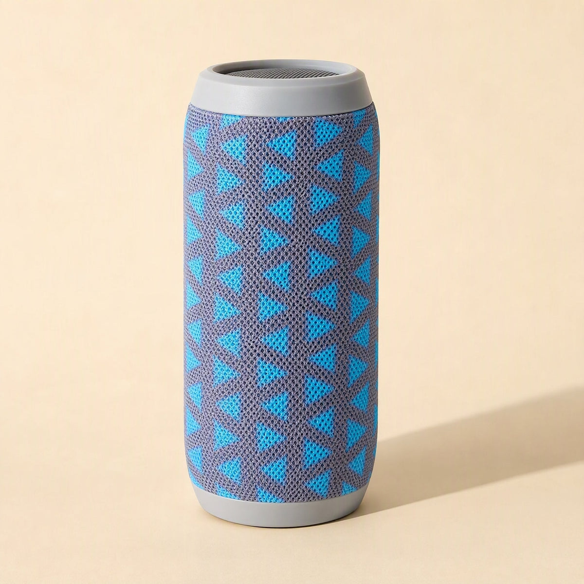 Pocketbeat – Upright speaker with blue triangle pattern on grey fabric, grey top and base rings, beside soft shadow