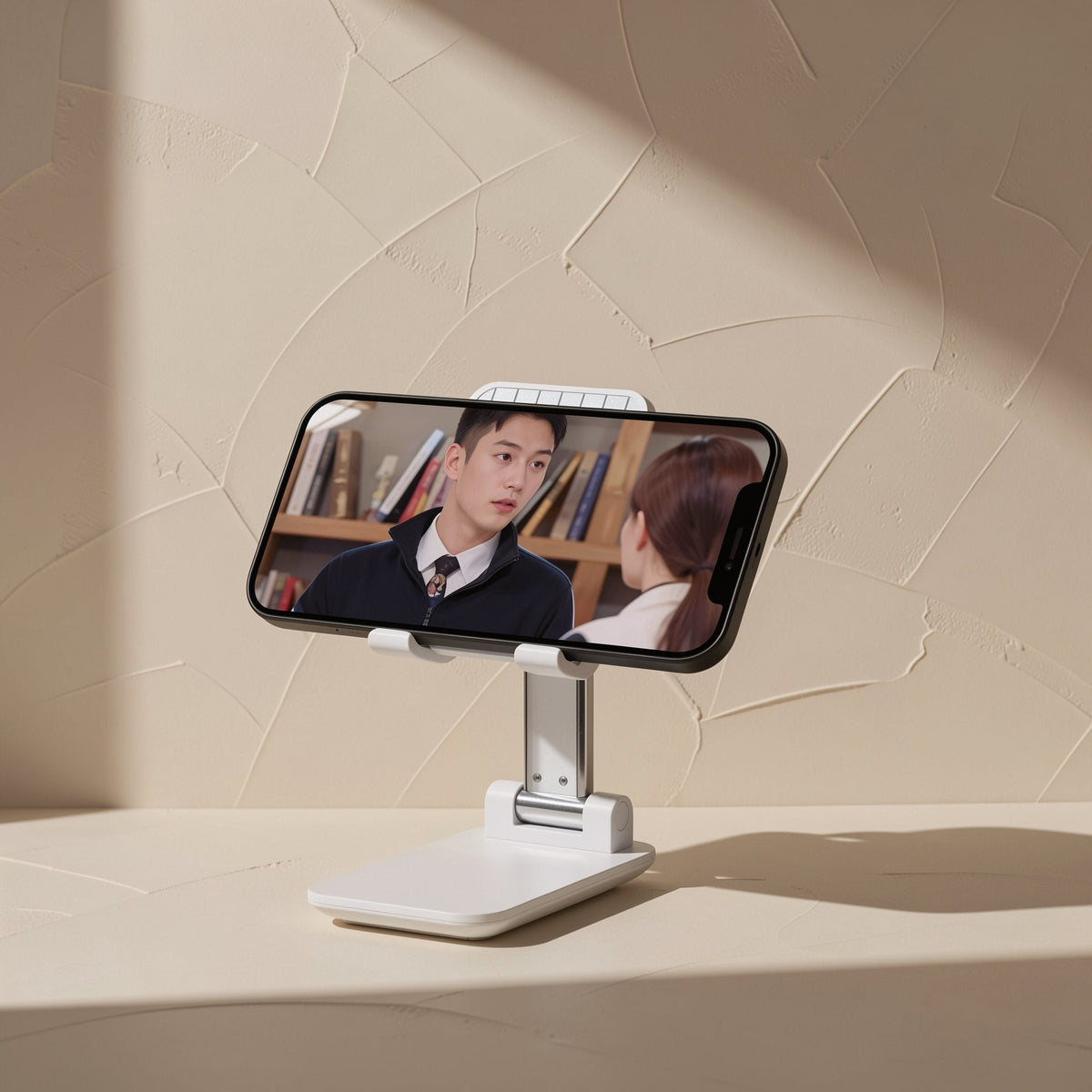Foldprop – Phone stand holding a smartphone in landscape showing a video of two people talking in a library