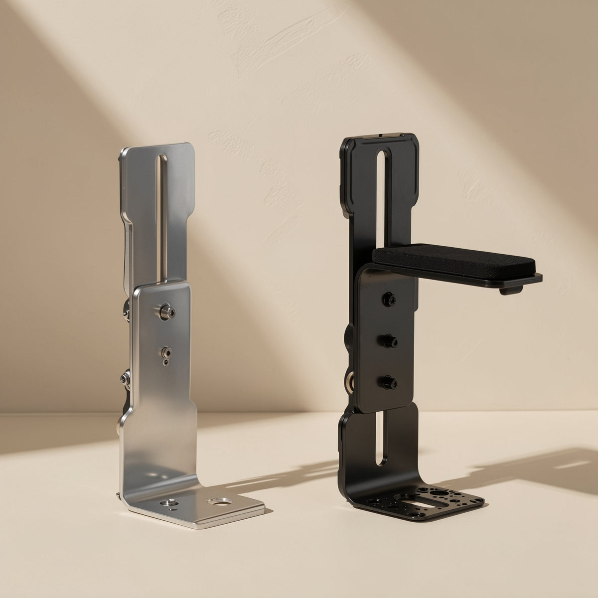 Anglehold – Silver and black L-shaped brackets side by side, the black one with a flat support pad and perforated base