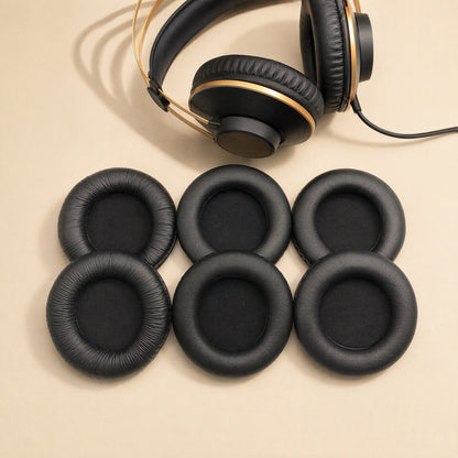 Earcush AKG K52 K72 K92 earpads, six black pads in three pairs beside a gold-banded headphone on beige