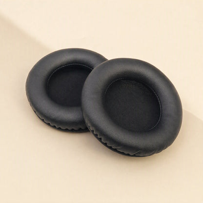 Earcush – Pair of black imitation leather earpads with smooth surface and dark fabric inner lining, angled view