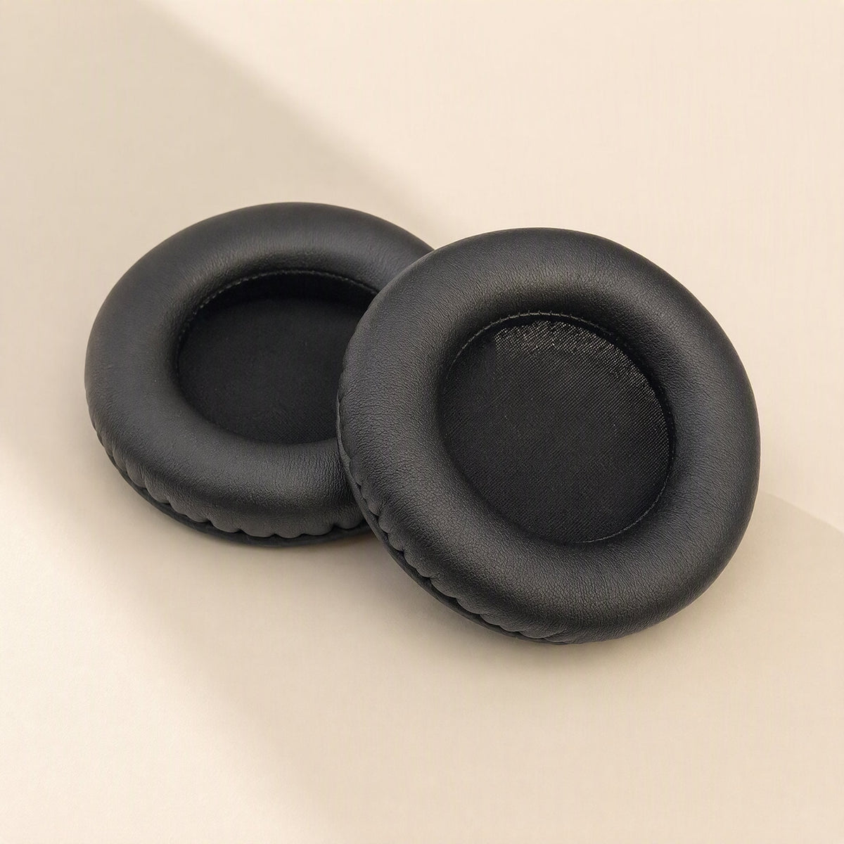 Earcush – Two black round earpads shown from a different angle, revealing the soft inner cushion opening