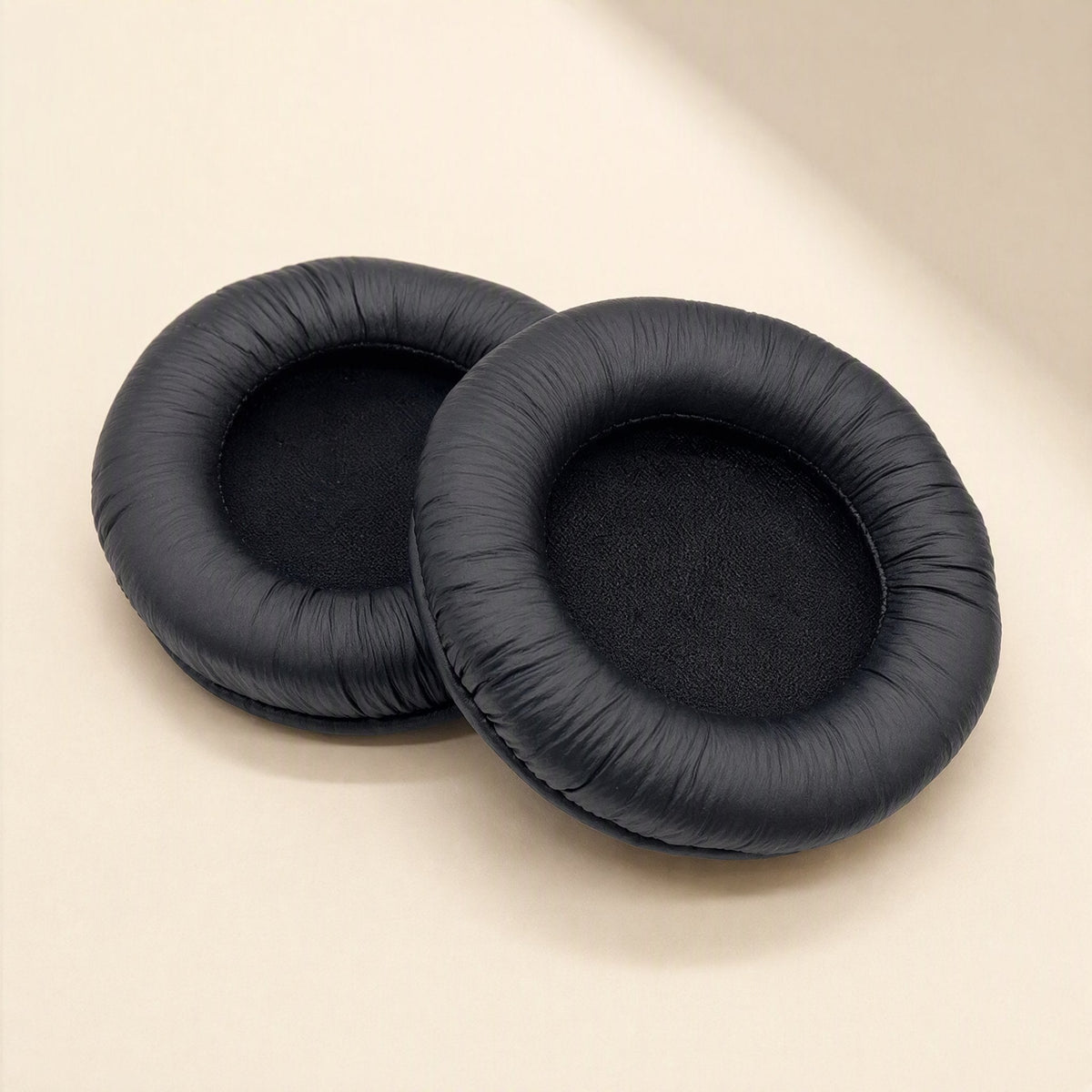 Earcush – Pair of black earpads with ridged, textured leather edges and a rounded cushion profile