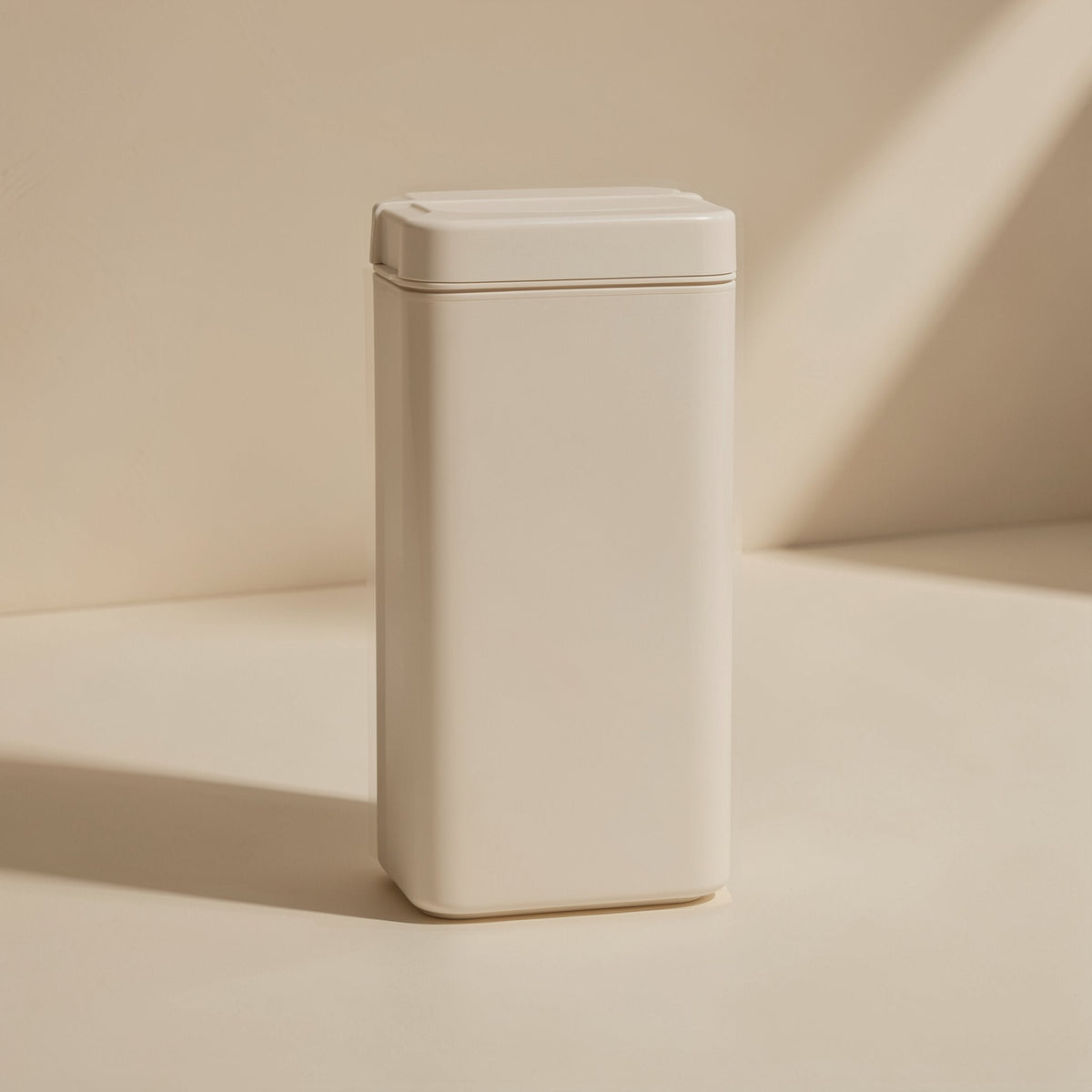 Slotread – Cream-coloured rectangular tin or case with a lidded top, standing upright against a beige wall