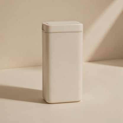 Slotread – Cream-coloured rectangular tin or case with a lidded top, standing upright against a beige wall