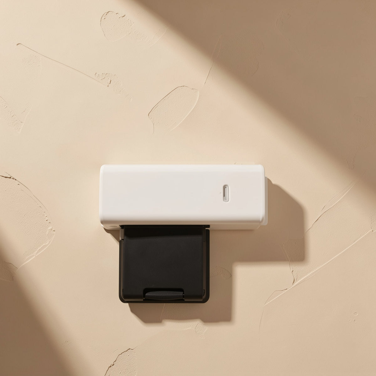 Slotread – Top view of a white USB card reader with a black SD card tray slid out, on textured beige plaster